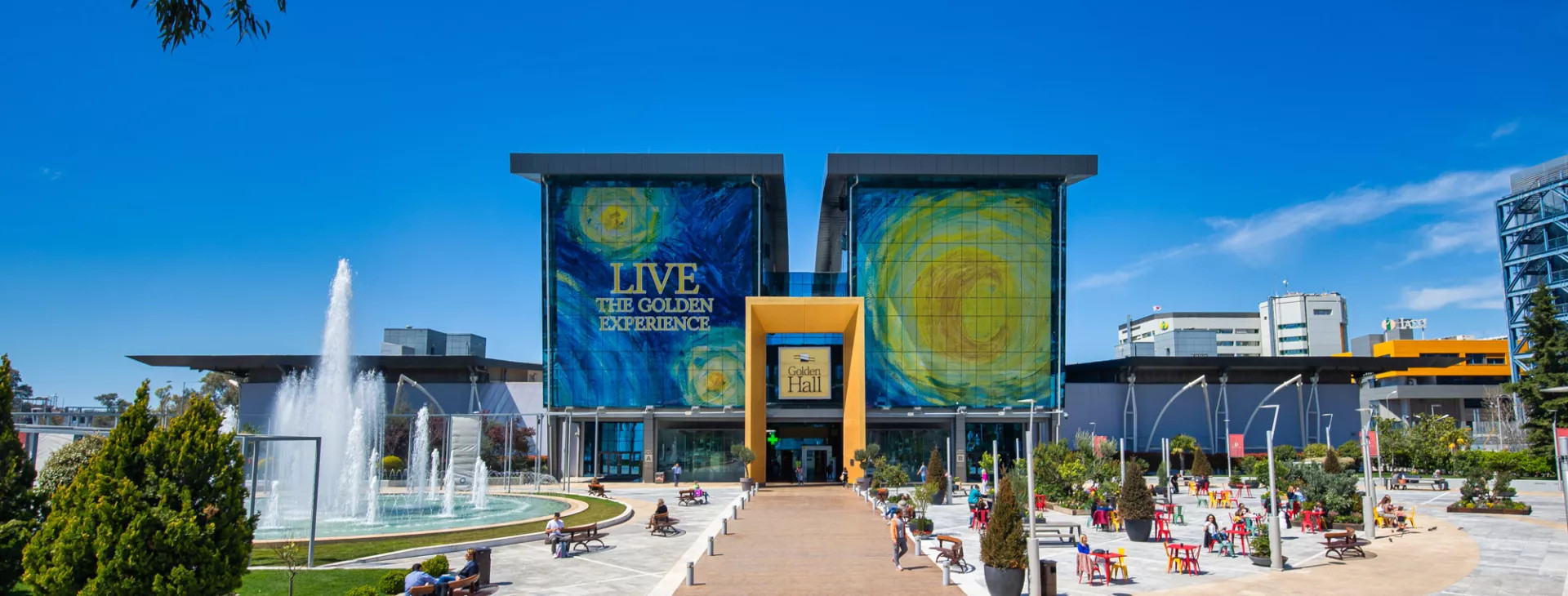 The mall in the middle, a fountain on the left and multi-colored tables with chairs on the right.