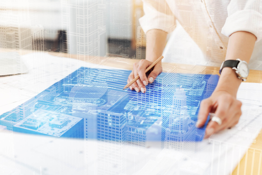 A woman in an office examines digital 3D models of buildings.